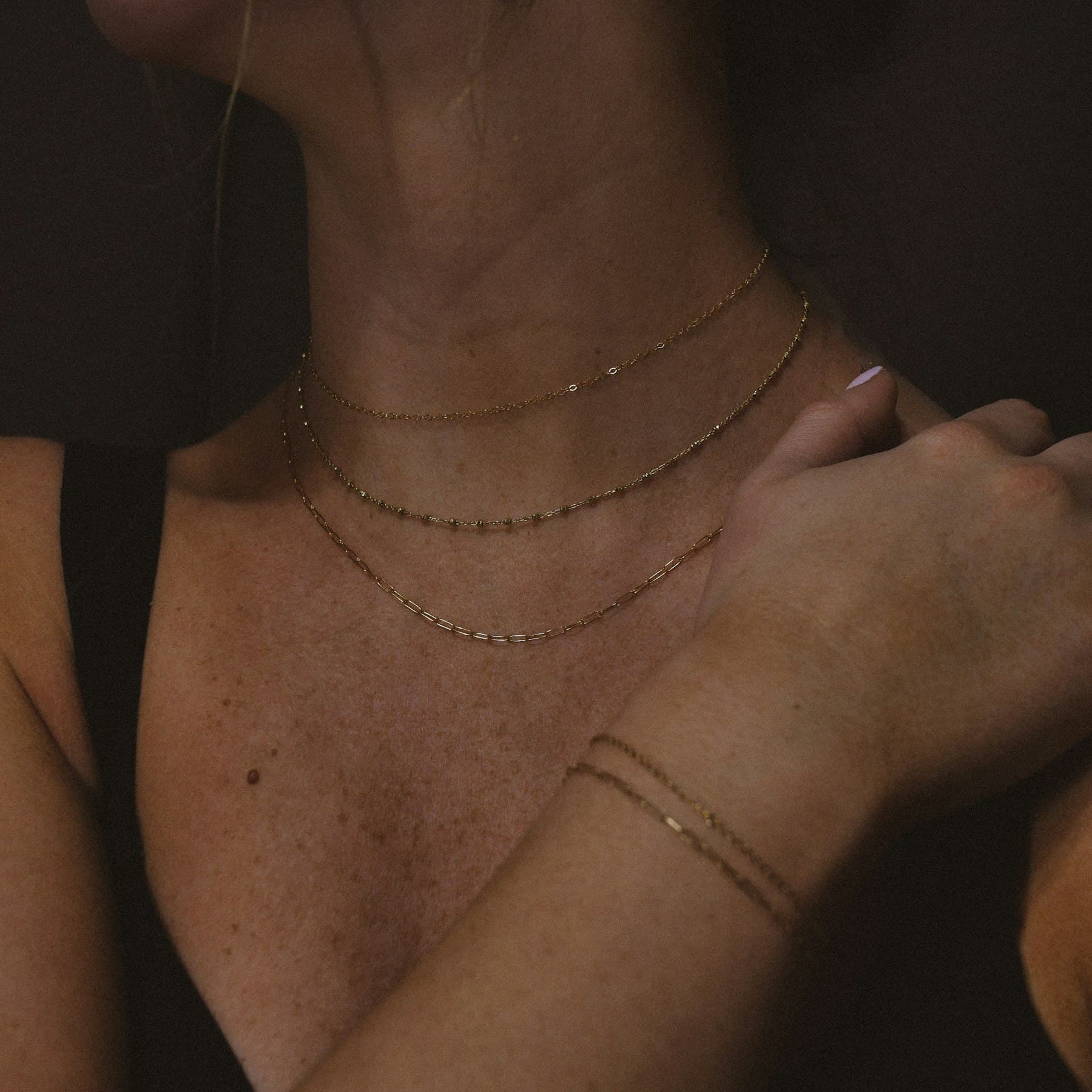 Delicate layered gold necklaces resting on skin